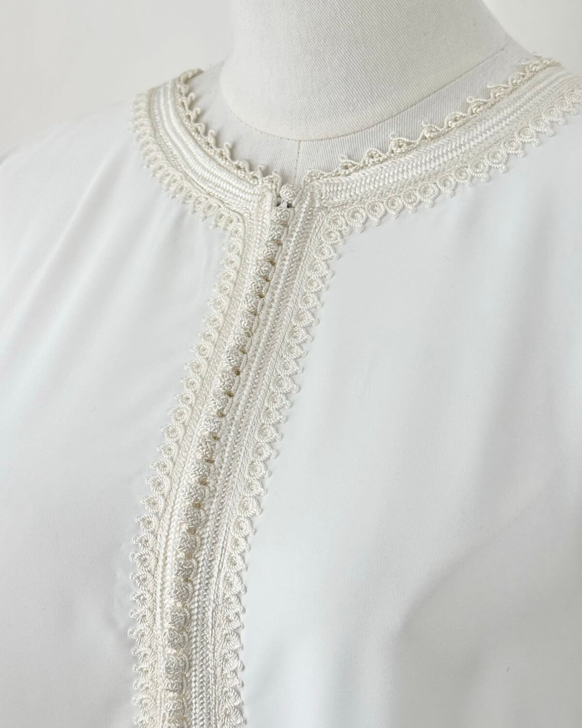 mannequin portant abaya femme matiere legere de couleur blanche avec un travail finition faite main vue motifs