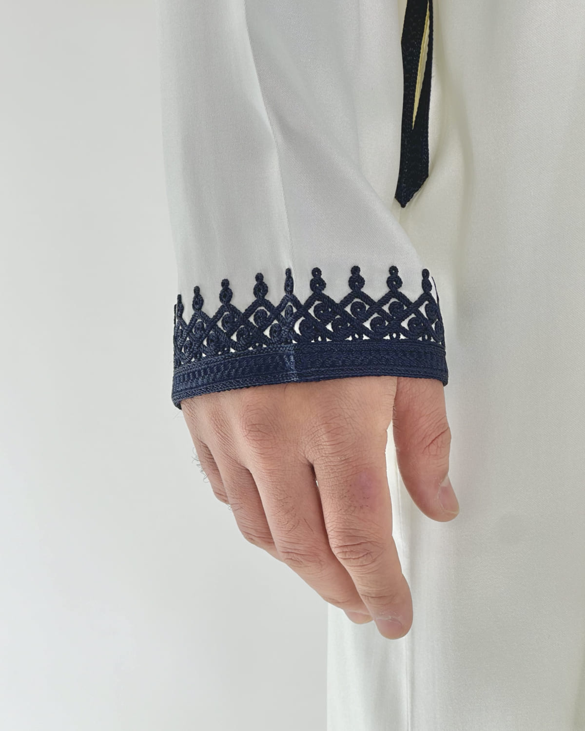 mannequin portant caftan homme matiere mlifa de couleur blanc-et-bleu avec un travail finition faite main vue manche