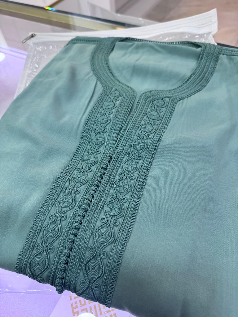 gandoura bleue avec motifs fait mail, pliée sur une table