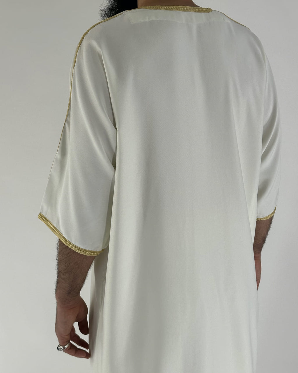 mannequin portant gandoura homme matiere gabardine de couleur blanc-et-or avec un travail motifs traditionnels brodés vue dos