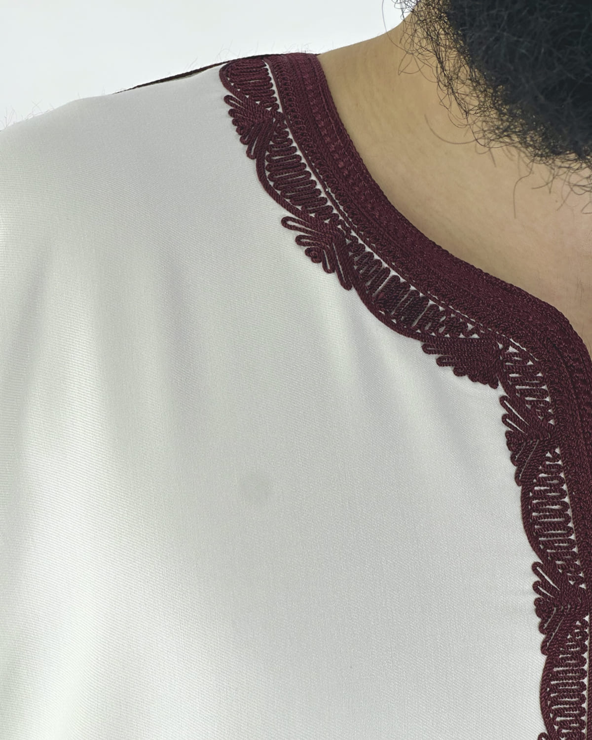 mannequin portant gandoura homme matiere gabardine de couleur blanc-et-rouge avec un travail motifs traditionnels brodés vue details-rapproches