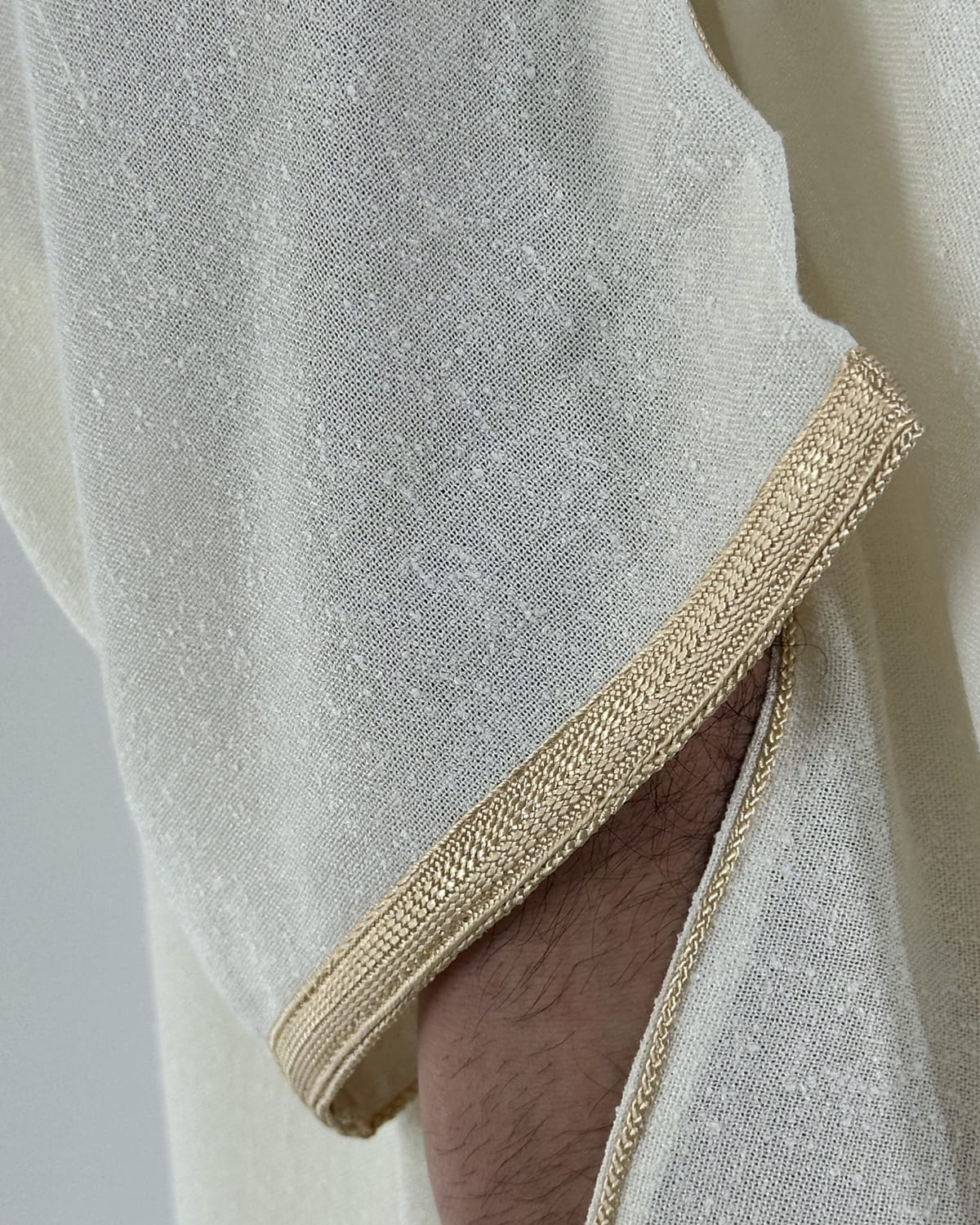 mannequin portant gandoura homme matiere lin de couleur beige avec un travail motifs fait main vue manche
